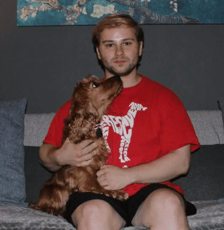 A photo of Paws2Rescue team member Matt sitting and holding a small dog